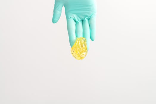 Yellow sugar paste in hand master of depilation. Smiling beautician holding wax for depilation over white background. Concept epilation. photo
