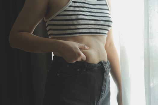 Women body fat belly. Obese woman hand holding excessive belly fat. diet lifestyle concept to reduce belly and shape up healthy stomach muscle. photo