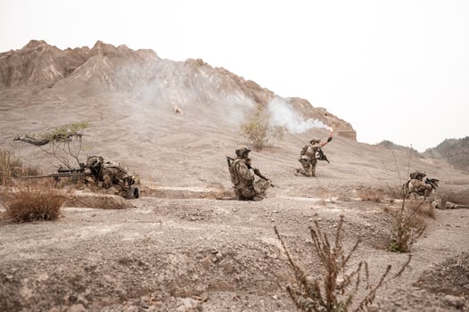 Soldiers in camouflage uniforms aiming with their riflesready to fire during military operation in the desert soldiers training in a military operation photo