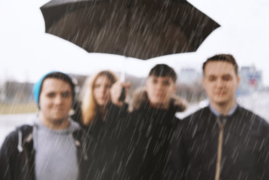 defocused group of young urban teenage friends under one umbrella photo