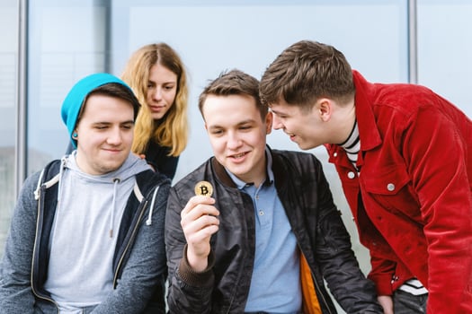 young man showing bitcoin coin to his intrigued group of friends photo