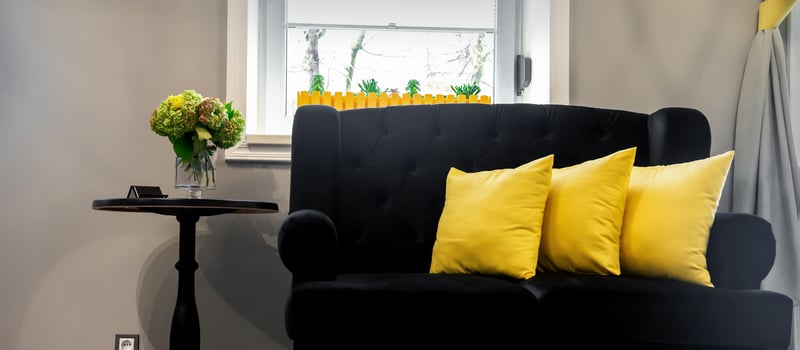 Interior of the beauty room. Black sofa with small yellow pillows and coffee table on a gray wall background with a window. photo