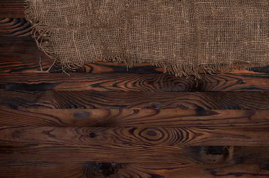 Old burlap fabric napkin on brown wooden background, top view photo