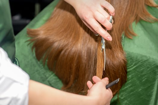 Hands of hairdresser cut woman long hair, close up. photo