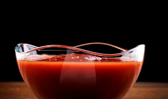 Ketchup in a glass cup on a wooden board. photo