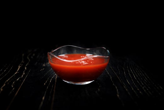 Ketchup in a glass cup on a black background. photo