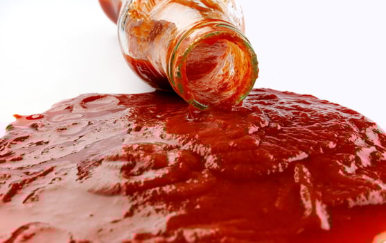 Tomato sauce . Glass bottle with ketchup. Ketchup is pouring out of the neck of a glass bottle. photo