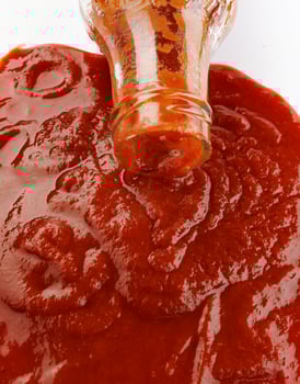 Tomato sauce . Glass bottle with ketchup. Ketchup is pouring out of the neck of a glass bottle. photo