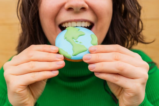 Earth Day concept. Woman bites into a cookie in the shape of the Earth. photo