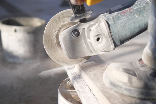 A person is using a grinder to cut an auto part made of steel photo