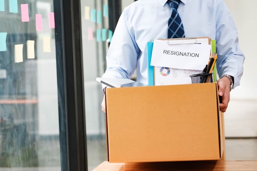 Man leaves office holding a box with personal items, including resignation letter. photo