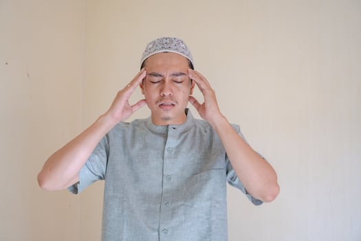 Moslem Asian man dizzy and headache face when Ramadan celebration. The photo is suitable to use for Ramadhan poster and Muslim content media.
