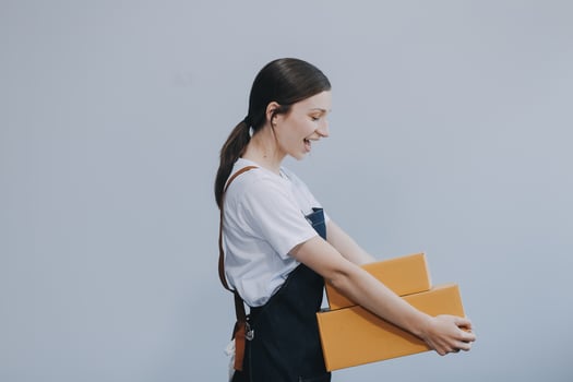 Smiling Asian woman in casual clothes holding a cardboard box mockup while standing against an isolated white background. shipping business concept photo