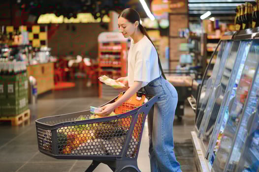 Happy young woman looking at product at grocery store. Smiling woman shopping in supermarket photo