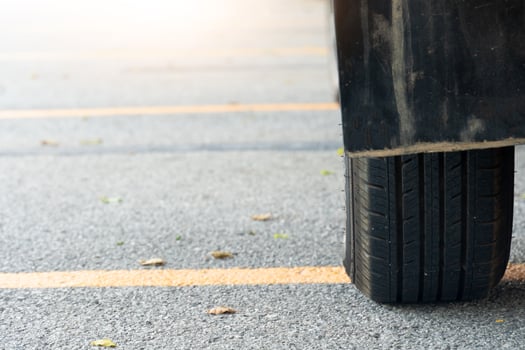 Close of used car tires on asphalt road with sun light in the morning time. With yellow line across the floor. photo