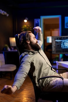 Software technician stretching after using computer all day to build artificial intelligence simulating human brain. Fatigued IT admin relaxing after finishing working with AI neural networks on PC photo
