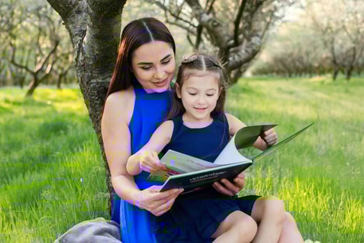 mother and daughter are reading together in the park photo
