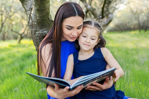 mother and daughter are reading together in the park photo