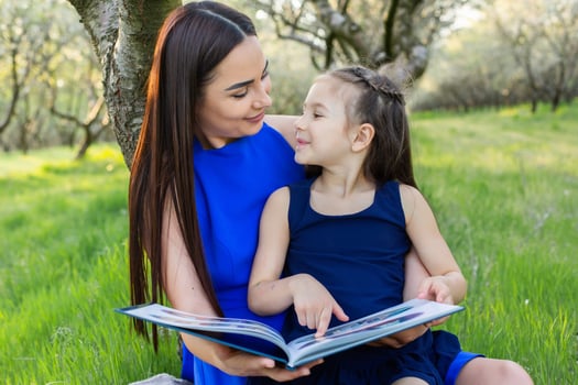 mother and daughter are reading together in the park photo