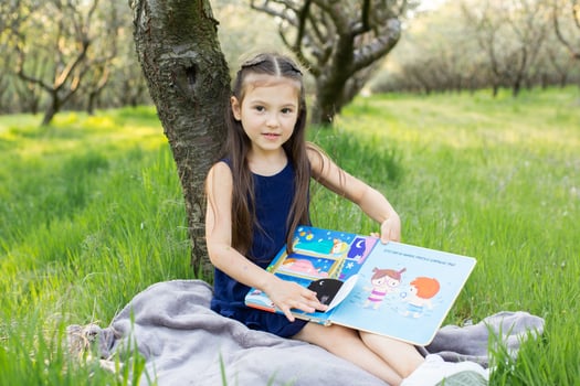 a child girl is reading a book in the park photo