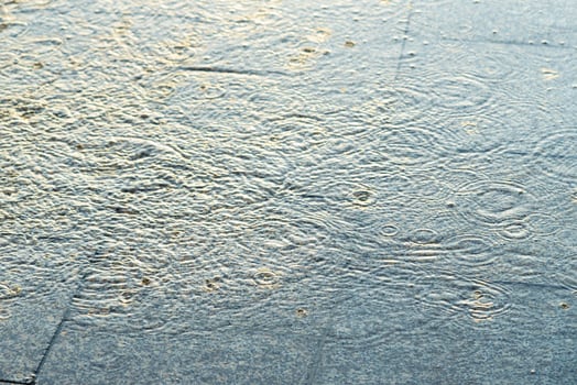 Splashes of water and raindrops on paving slabs. Rainy weather concept. photo