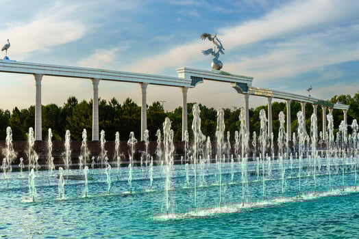 Memorial and rows of fountains illuminated by sunlight at sunset or sunrise in the Independence Square at summertime, Tashkent. photo