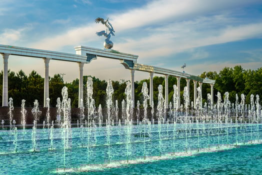 Memorial and rows of fountains illuminated by sunlight at sunset or sunrise in the Independence Square at summertime, Tashkent. photo