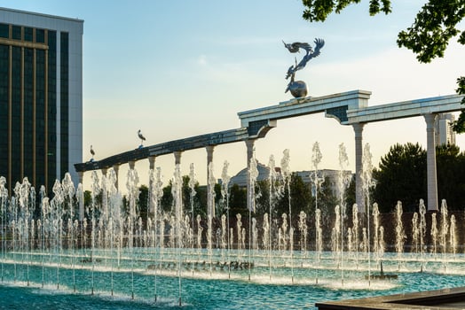 Memorial and rows of fountains illuminated by sunlight at sunset or sunrise in the Independence Square at summertime, Tashkent. photo