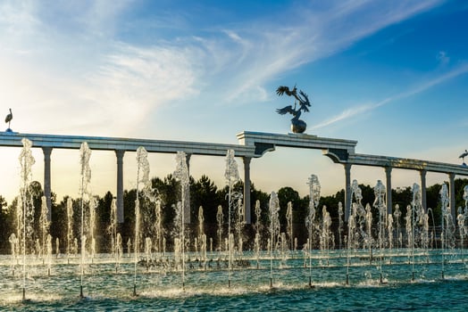 Memorial and rows of fountains illuminated by sunlight at sunset or sunrise in the Independence Square at summertime, Tashkent. photo