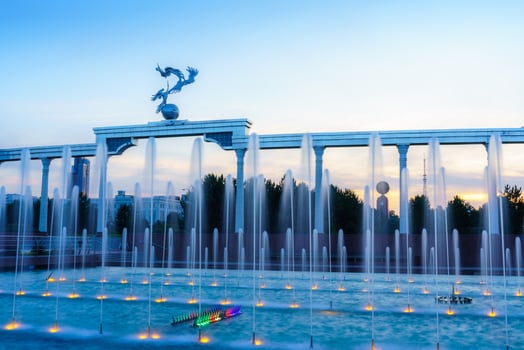 Memorial and rows of fountains illuminated by sunlight at sunset or sunrise in the Independence Square at summertime, Tashkent. photo