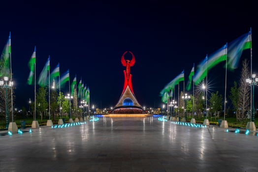 UZBEKISTAN, TASHKENT - MAY 5, 2023 Illuminated monument of independence in the form of a stele with a Humo bird, fountains and waving flags in the New Uzbekistan park at nighttime. photo