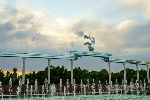 Memorial and rows of fountains illuminated by sunlight at sunset or sunrise in the Independence Square at summertime, Tashkent. photo