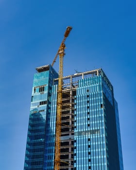 A crane building a skyscraper against a blue sky. photo
