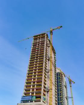 A crane building a skyscraper against a blue sky. photo