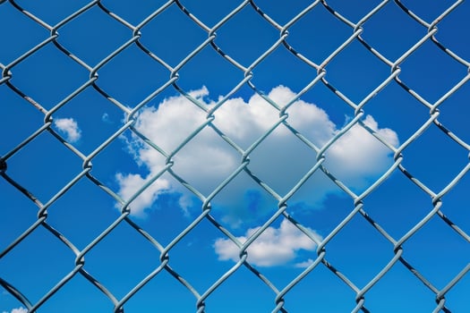 A cloud is seen through a chain link fence photo