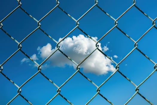 A cloud is seen through a chain link fence photo