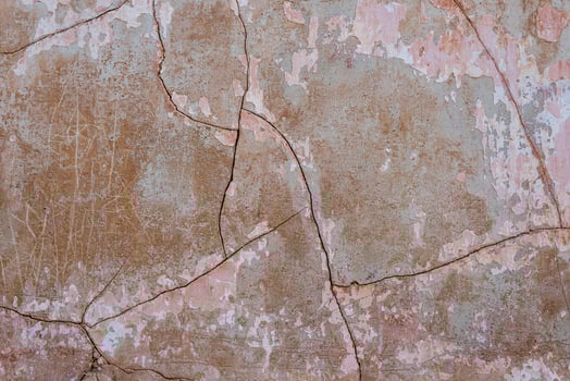 Old gray concrete wall with cracks and scratches covered with shabby pink plaster photo