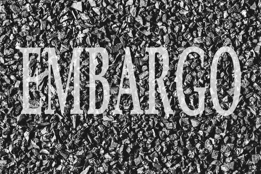 The word Embargo on a background of coal. The concept of an embargo on the supply of coal. photo
