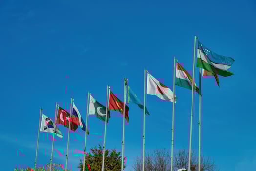 Flags of uzbekistan, japan, south korea, turkmenistan, kyrgyzstan, kazakhstan, turkish and russian against the blue sky. photo