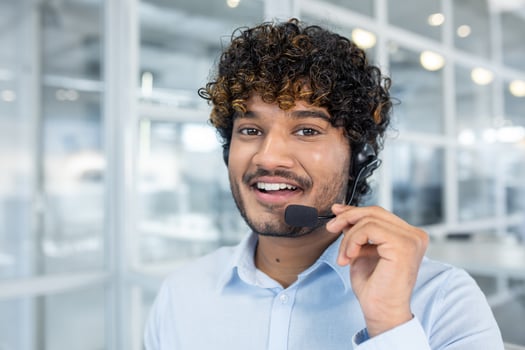 A cheerful customer service representative wearing a headset in a contemporary office environment. His friendly demeanor suggests approachability and professionalism. photo
