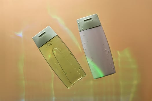 Shampoo and hair conditioner in water on a beige background. View from below. photo