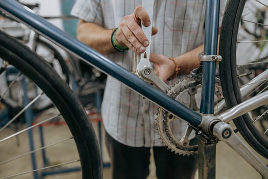 Cropped shot of male mechanic working in bicycle workshop. Bike service, repair and upgrade photo