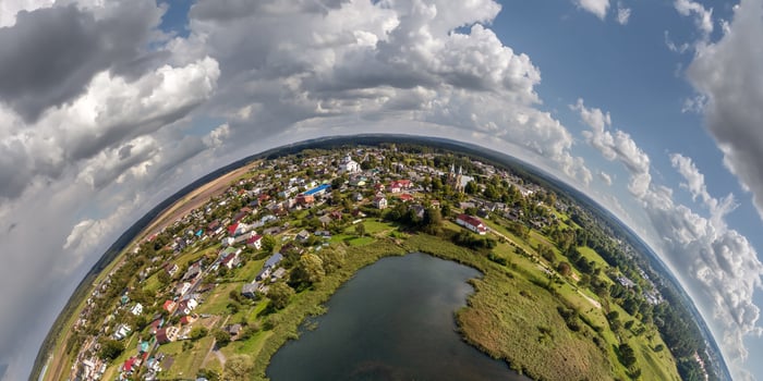 Aerial view from high altitude tiny planet in sky with clouds overlooking old town, urban development, buildings and crossroads. Transformation of spherical 360 panorama in abstract aerial view. photo