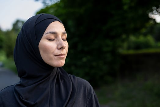 A Muslim woman wearing a hijab stands amidst lush greenery, symbolizing serenity and the connection between faith and nature. photo
