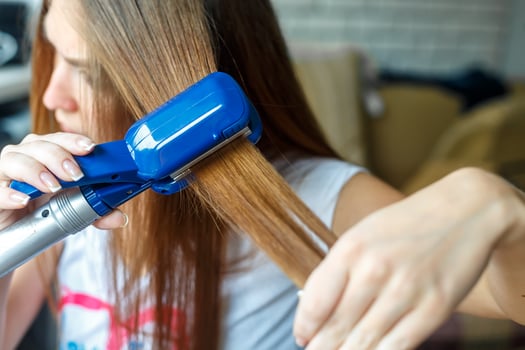 Hairdresser hairstyle models using the straightener. Closeup. Selective focus. photo