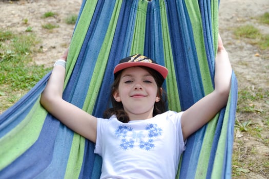 A beautiful girl lies in a yellow hammock on a background of blurred greenery. photo