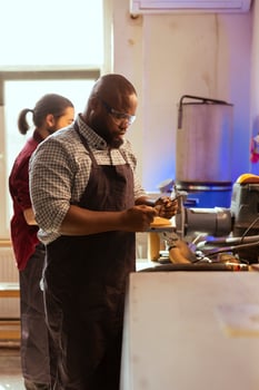 African american carpenter looking at screwdriver, preparing to start production in furniture assembly shop. BIPOC cabinetmaker at workbench inspecting tool, ready to work on wood designs photo