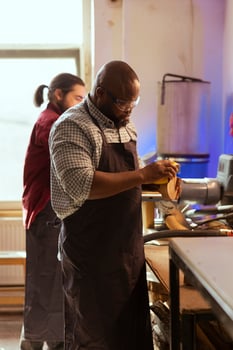 African american artisan in studio using sandpaper for smoothing wooden surface, creating wood art designs. BIPOC person using sanding sheets to refurbish damages suffered by timber block photo