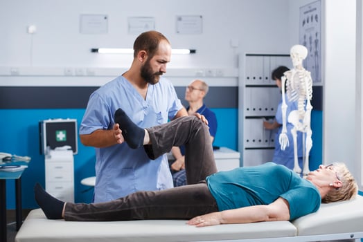 Physiotherapist stretching leg muscle to relieve pressure for recovery of senior woman. Doctor assistant helping aged patient with knee pain, doing physical exercise for physical therapy. photo
