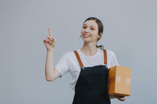 Smiling Asian woman in casual clothes holding a cardboard box mockup while standing against an isolated white background. shipping business concept photo